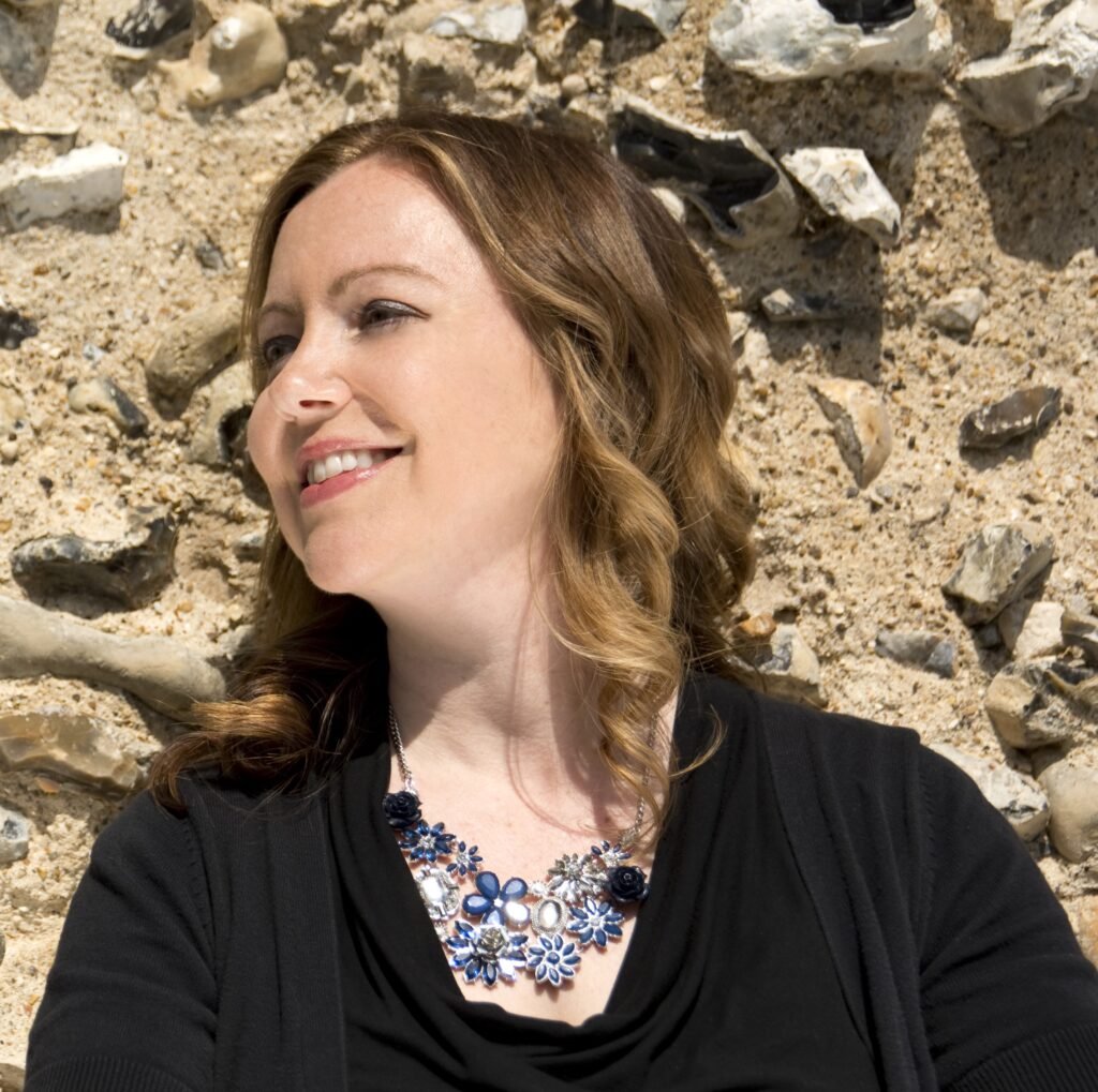 Jennifer smiling outdoors against a stone wall